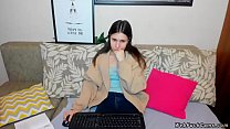 Brunette amateur teen sitting in clothes on the couch and typing on her keyboard while getting remote controlled vibrations from users of webcam show